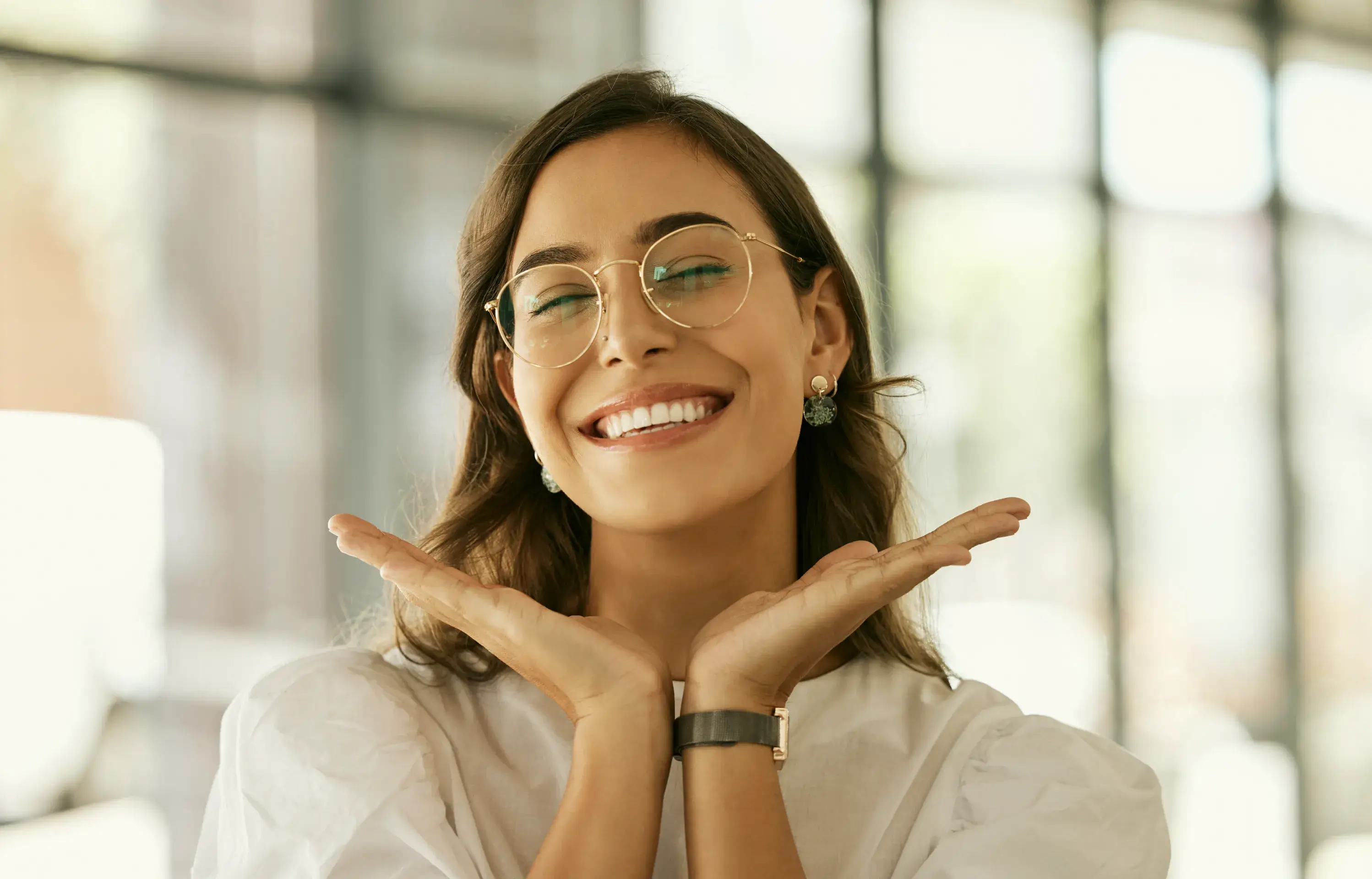 a woman wearing glasses making a gesture with her hands